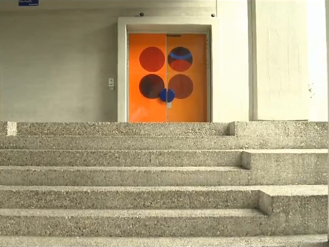 Eine Betontreppe führt zu einer orangen Keramiktür