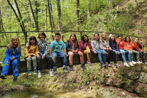 Bild Ferienhort Kinder sitzen in einer Reihe auf einer Brücke im Wald 