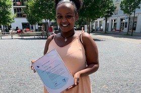 Luwam Tekle hält ihr Diplom zur Restaurantfachfrau (EFZ) in der Hand und lacht