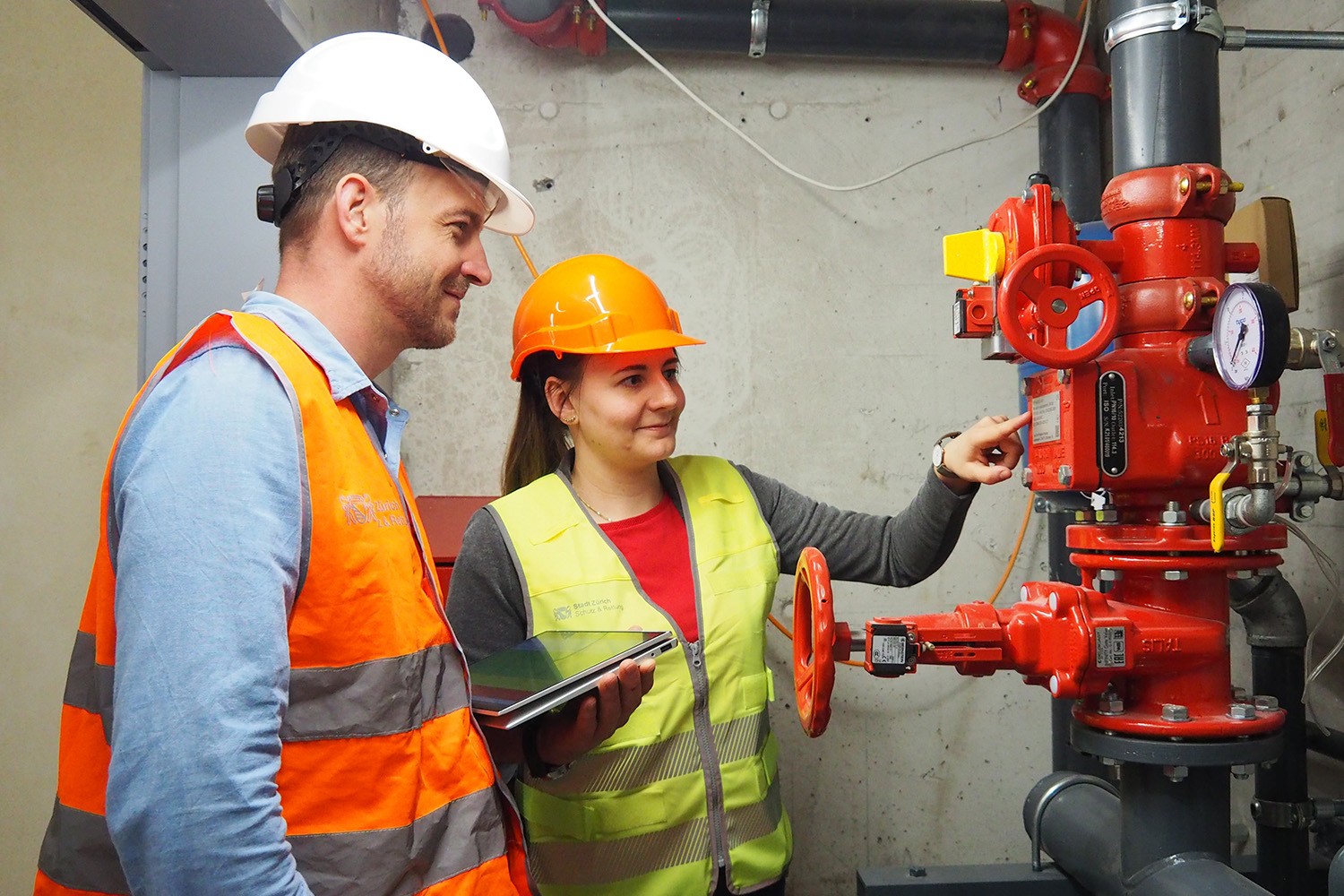 Zwei Mitarbeitende der Feuerpolizei kontrollieren eine Sicherheitsanlage. 