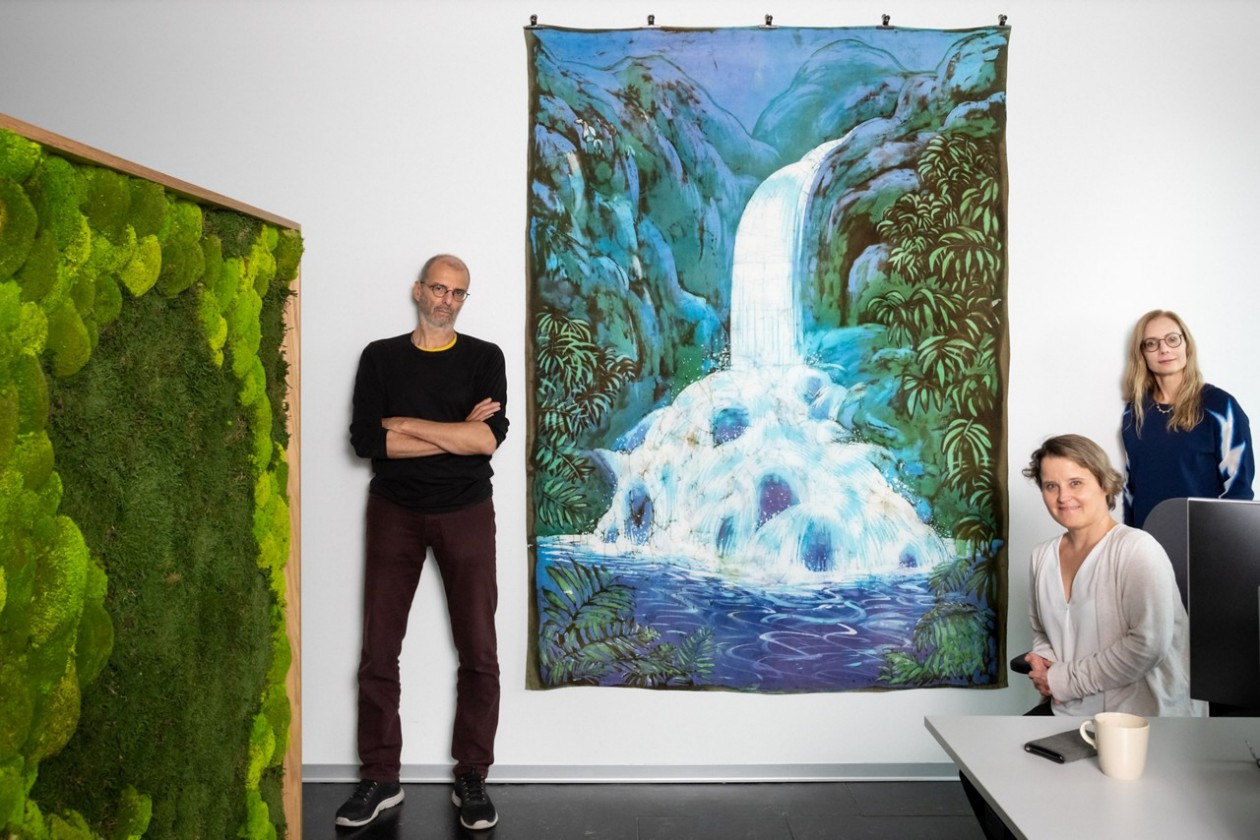 Das Team von Soziale Betrieb und Einrichtungen, stehend und sitzend vor dem Kunstwerk «Wasserfall II» von Andreas Dobler