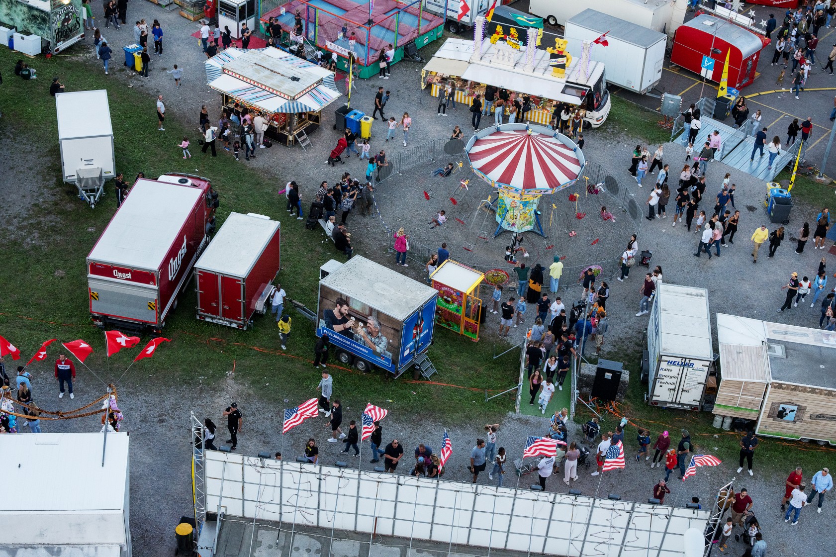 Luftaufnahme des Knabenschiessens in Zürich: Zwischen Marktständen und einem Karussell bewegen sich Menschen, teils in kleinen Gruppen, teils einzeln.