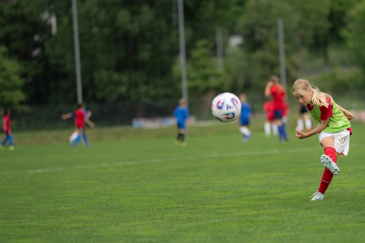 Das Bild zeigt ein Mädchen in Fussballkleidung, das einen Ball kickt. 