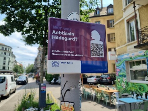Violettes Schild an einer Strassenlaterne mit QR-Code und der Aufschrift: «Wer war Äbtissin Hildegard?»