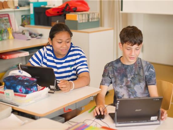 Eine Schülerin und ein Schüler arbeiten mit Tablets in der Schule