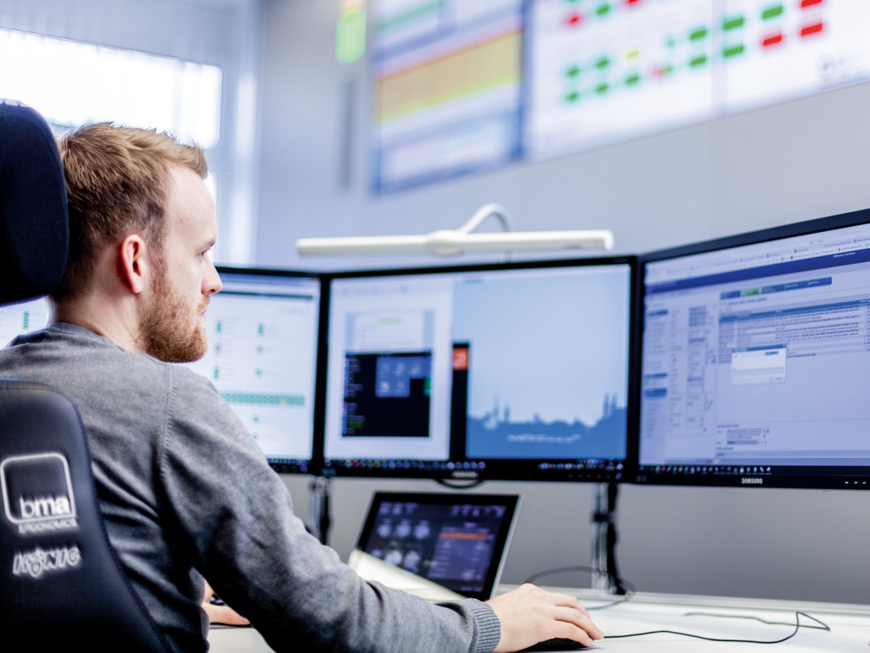 Cyber Security Spezialist arbeitet vor drei Monitoren
