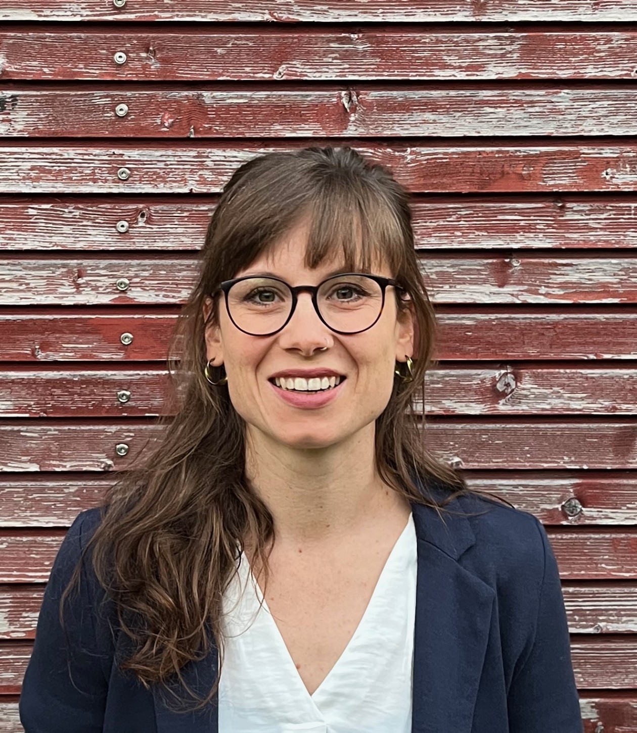 Ursina Krähenmann mit runder Brille und langen braunen Haaren mit einem schwarzen Blazer.