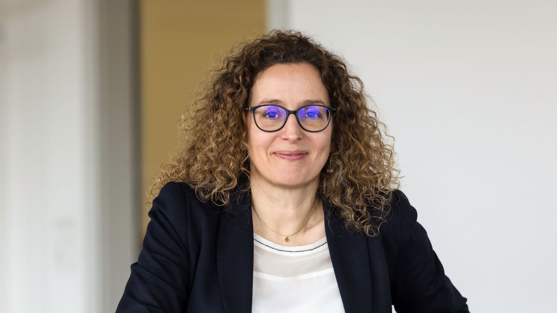 Ein lächelnder Mann mit Brille und Bart lehnt sich gegen eine Wand. Foto Alex Colle