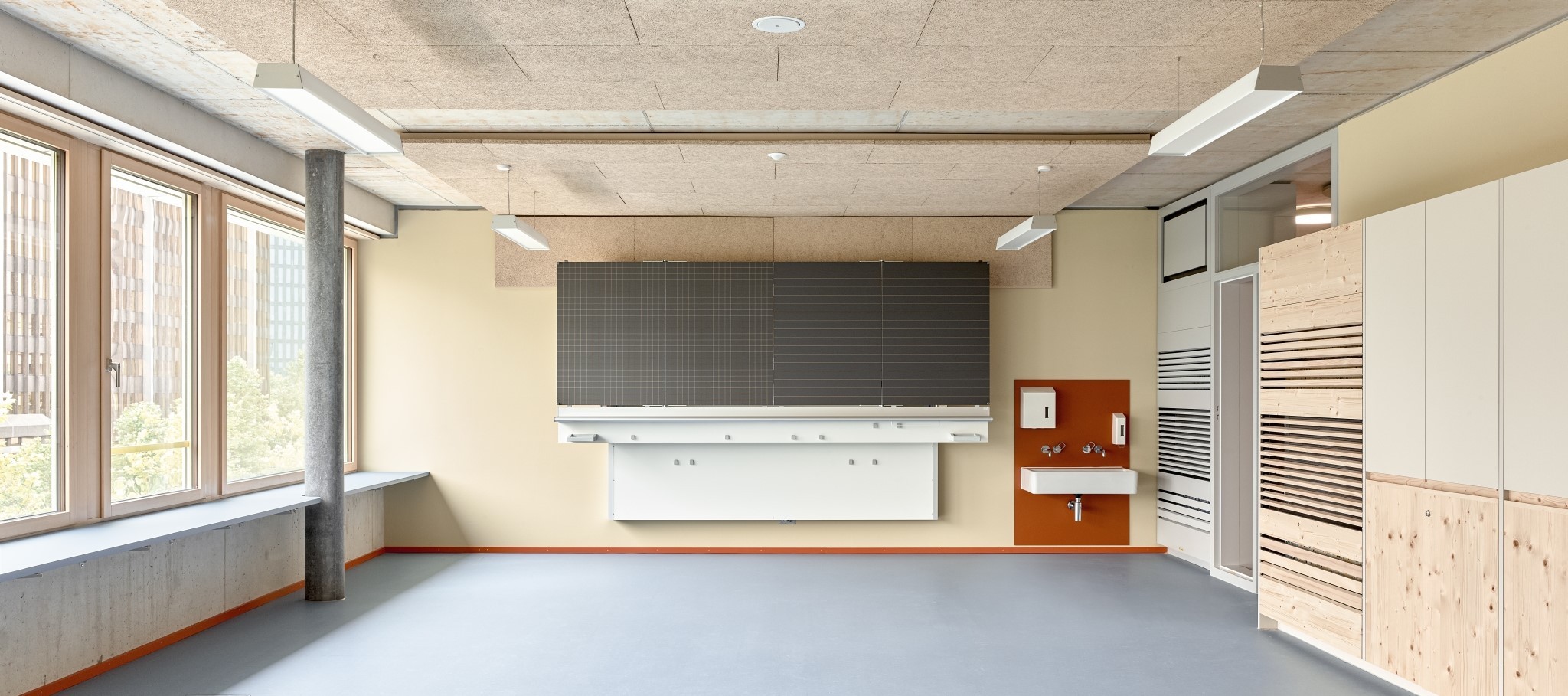 Leeres Schulzimmer mit grosser Wandtafel und Lüftungsschlitzen an der rechten Wand