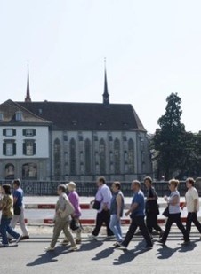 Eine Gruppe Tourist*innen läuft im Gänsemarsch der Limmat entlang.