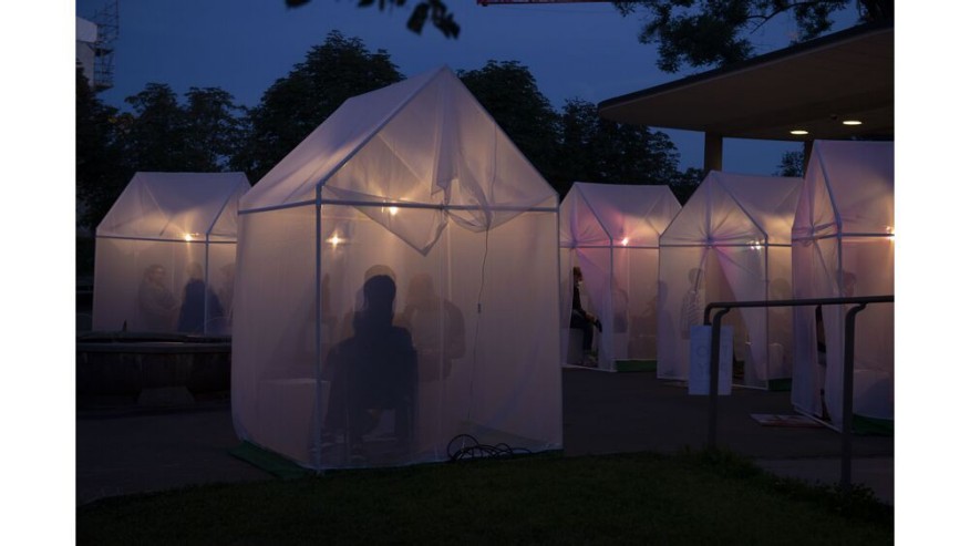 Auf dem Münsterhof stehen viele kleine durchscheinende Zelte, darin sieht man die Umrisse von Menschen an inem Tisch. 