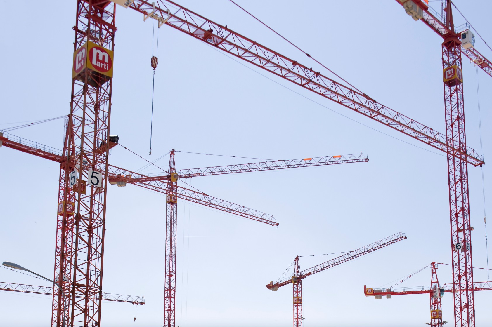 Der Rohbau eines Wohnblocks ist beinahe fertig, um den Block stehen Kranen, die an ihm arbeiten.