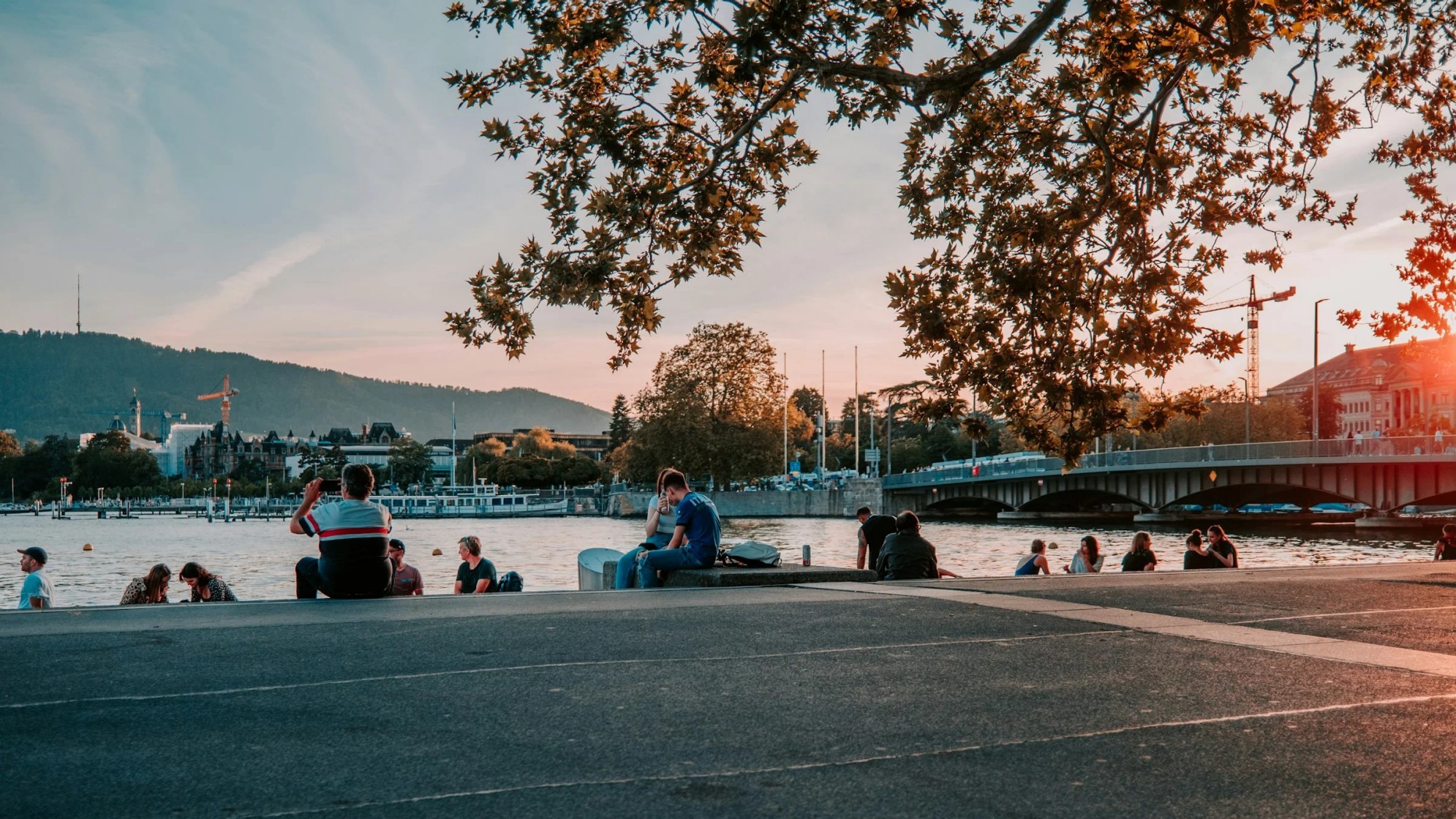 Der Utoqua bei Sonnenuntergang. mehrheitlich junnge leute sitzen auf den Treppenstufen und schauen auf den See.