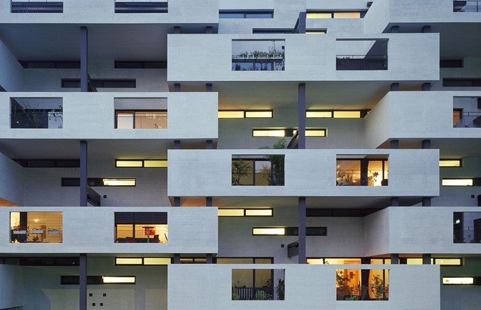 Eine Wohnüberbauung von aussen. Die Wohnungen und Balkone sind schachtelartig und versetzt angeordnet.
