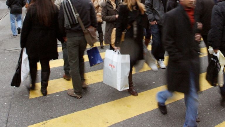 Eine Menge läuft über einen Fussgängerstreifen, man sieht nur ihre Beine und Taschen.
