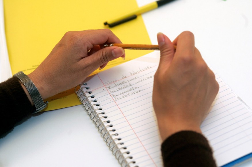 Die Hände einer Kursteilnehmerin sind auf dem Tisch, unter ihnen ein Notizblock und Papiere