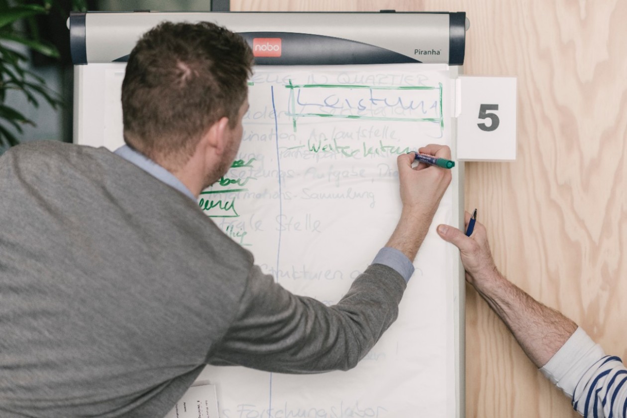 Ein junger Mann schreibt auf ein Flip-Chart.
