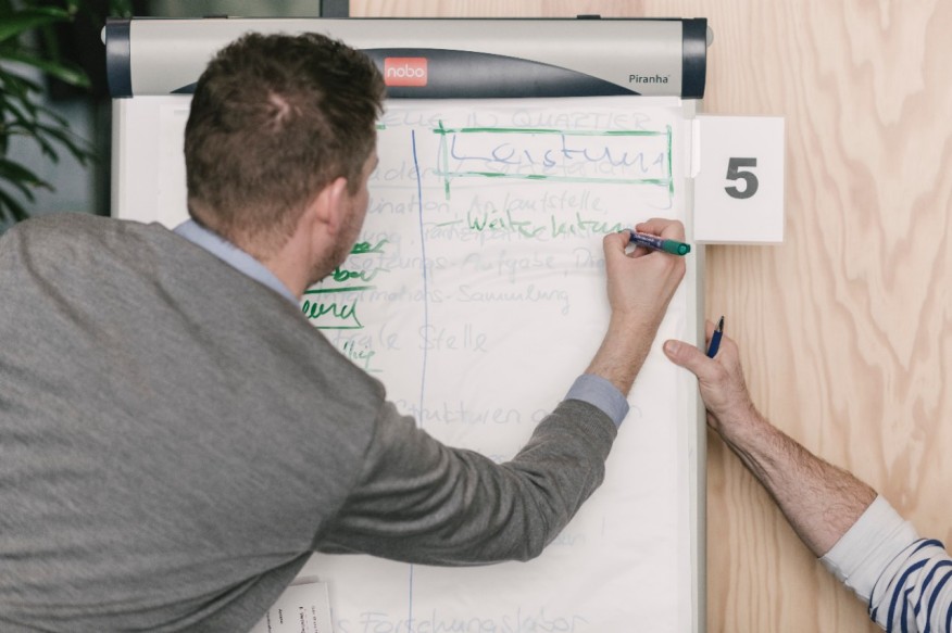 Ein junger Mann schreibt auf ein Flip-Chart.