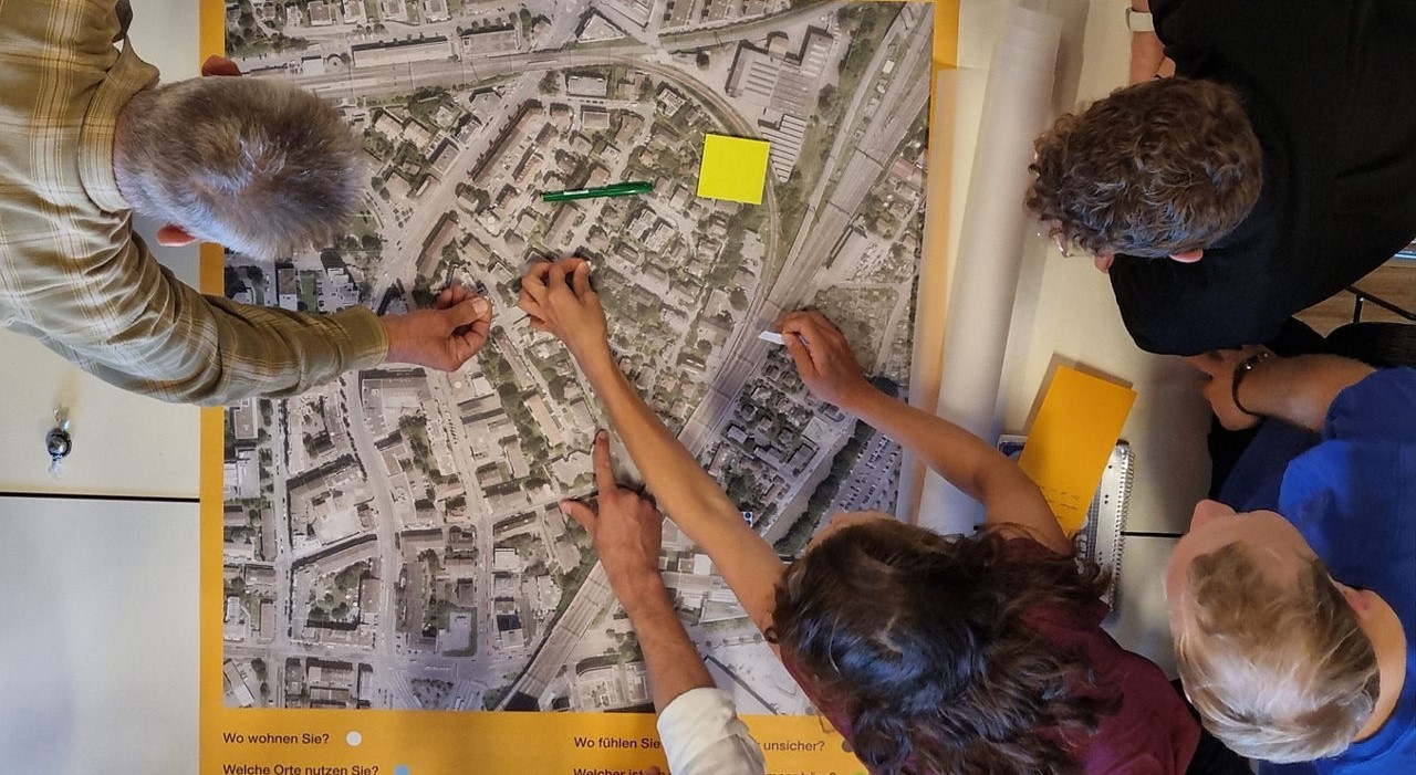 Ein Quartierplan hängt an der Wand und daran mehrere Post-its.