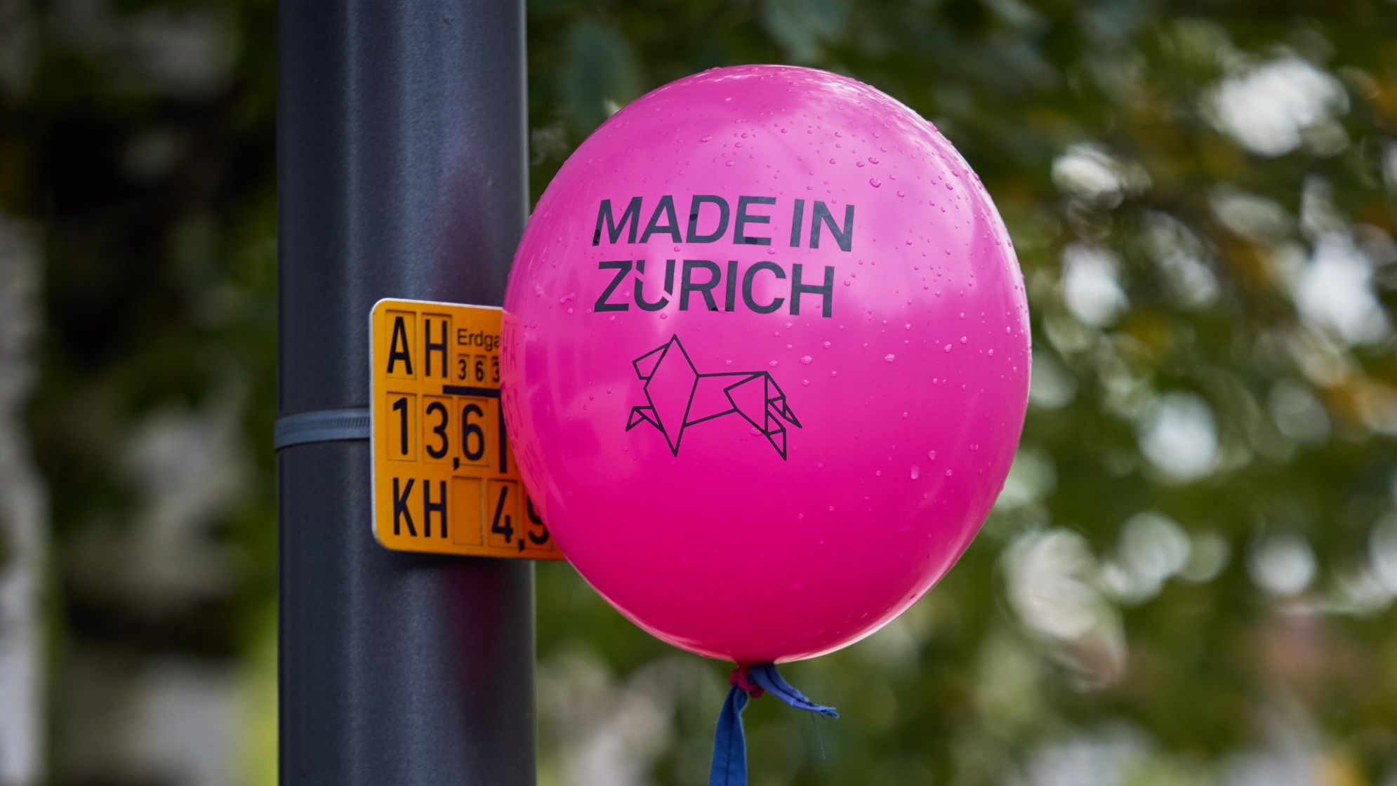 Ein pinker Luftballon hängt am Pfahl einer Strassenlampe. Darauf steht: Made in Zurich.