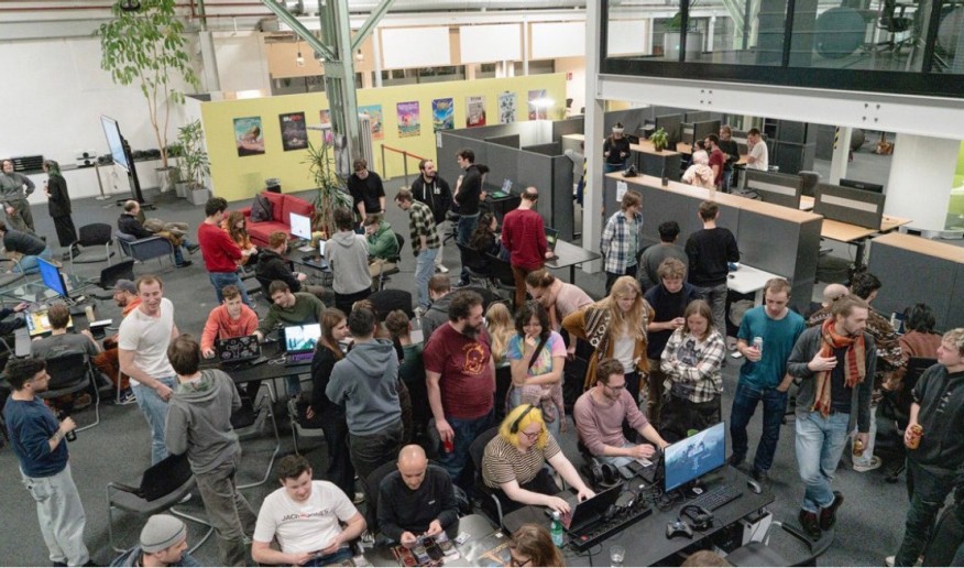 Blick von oben am Playtesting Event: Junge sitzen an Computern oder stehen an Tischen und testen Computer Games.