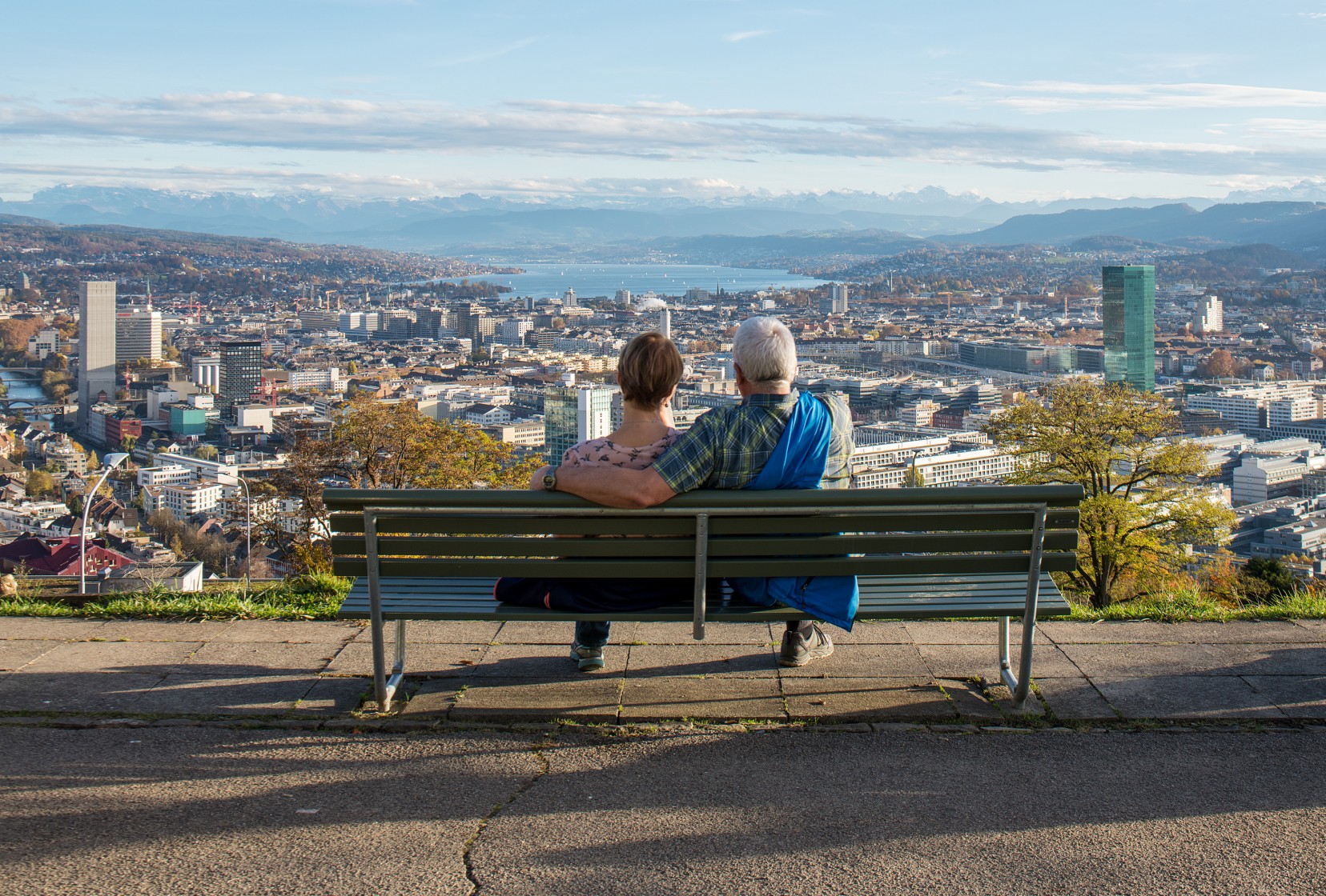 Ein Paar sitzt auf einer Bank und geniesst die Aussicht auf Zürich.
