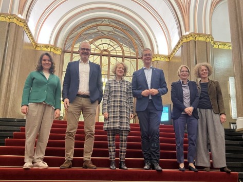 Besuch_Evers Die Zürcher Delegation und der Berliner Bürgermeister stehen auf einer Treppe in einem pompösen Gebäude.