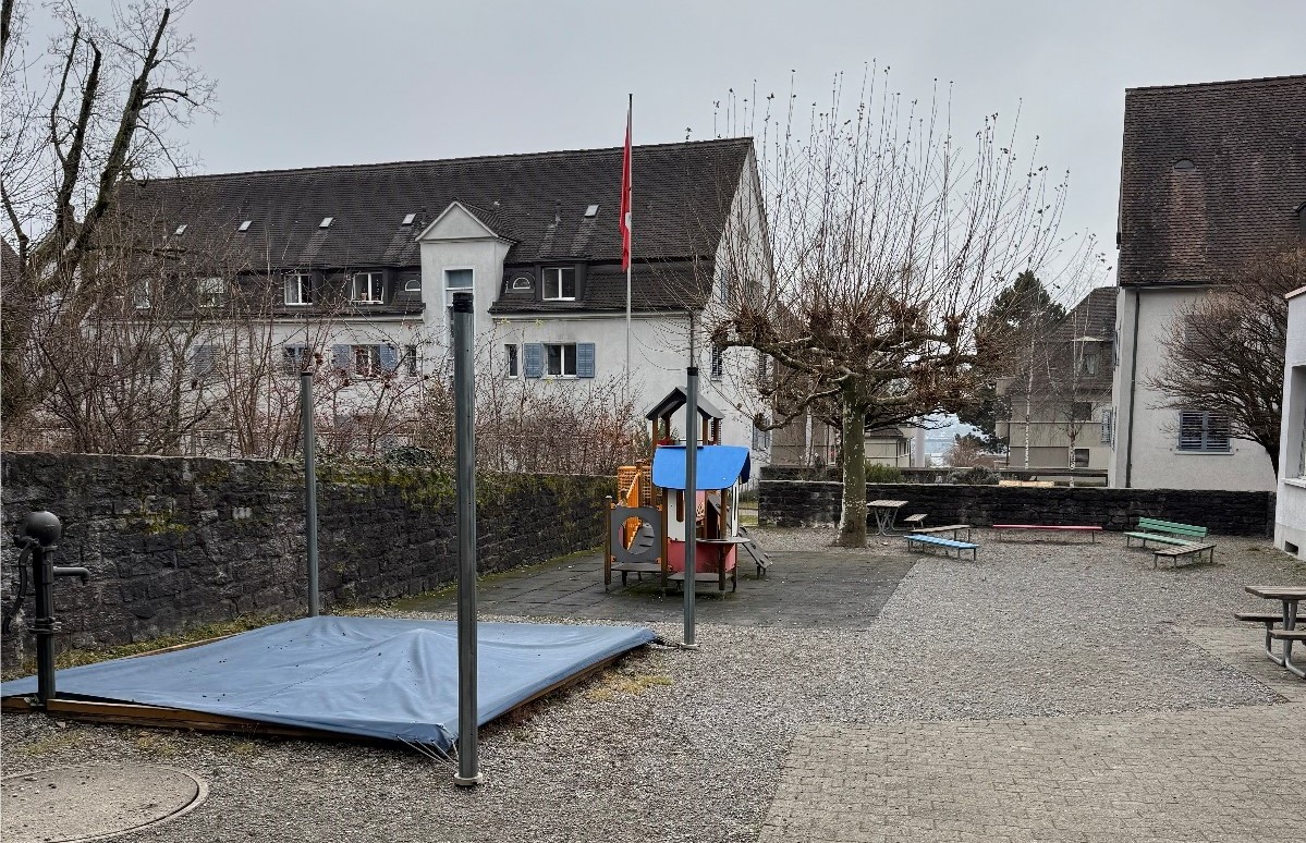 Aussenraum vom Kindergarten Zeppelin mit abgedecktem Sandkasten und Kletterturm