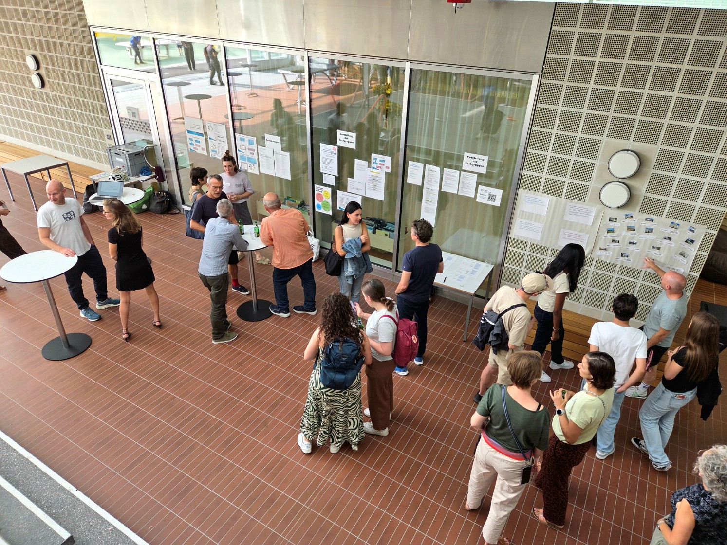 Mitarbeitende stehen an Stehtischen und unterhalten sich, Blick von oben.