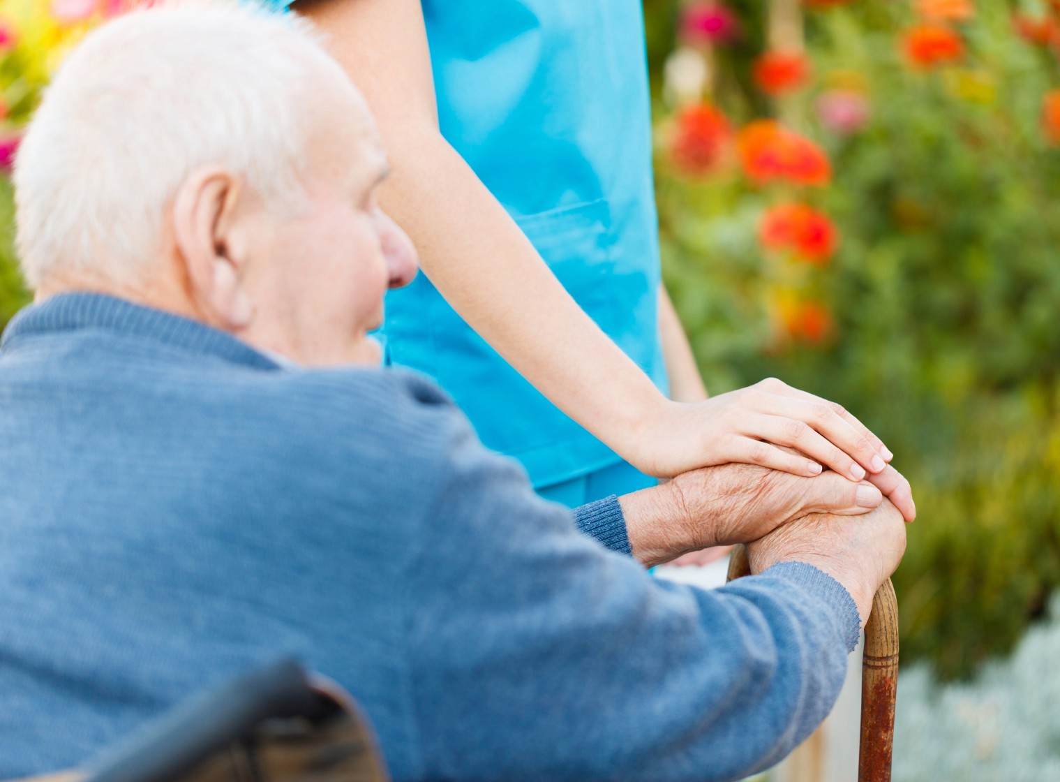 Pflegefachfrau legt Hand auf die Hände des Seniors