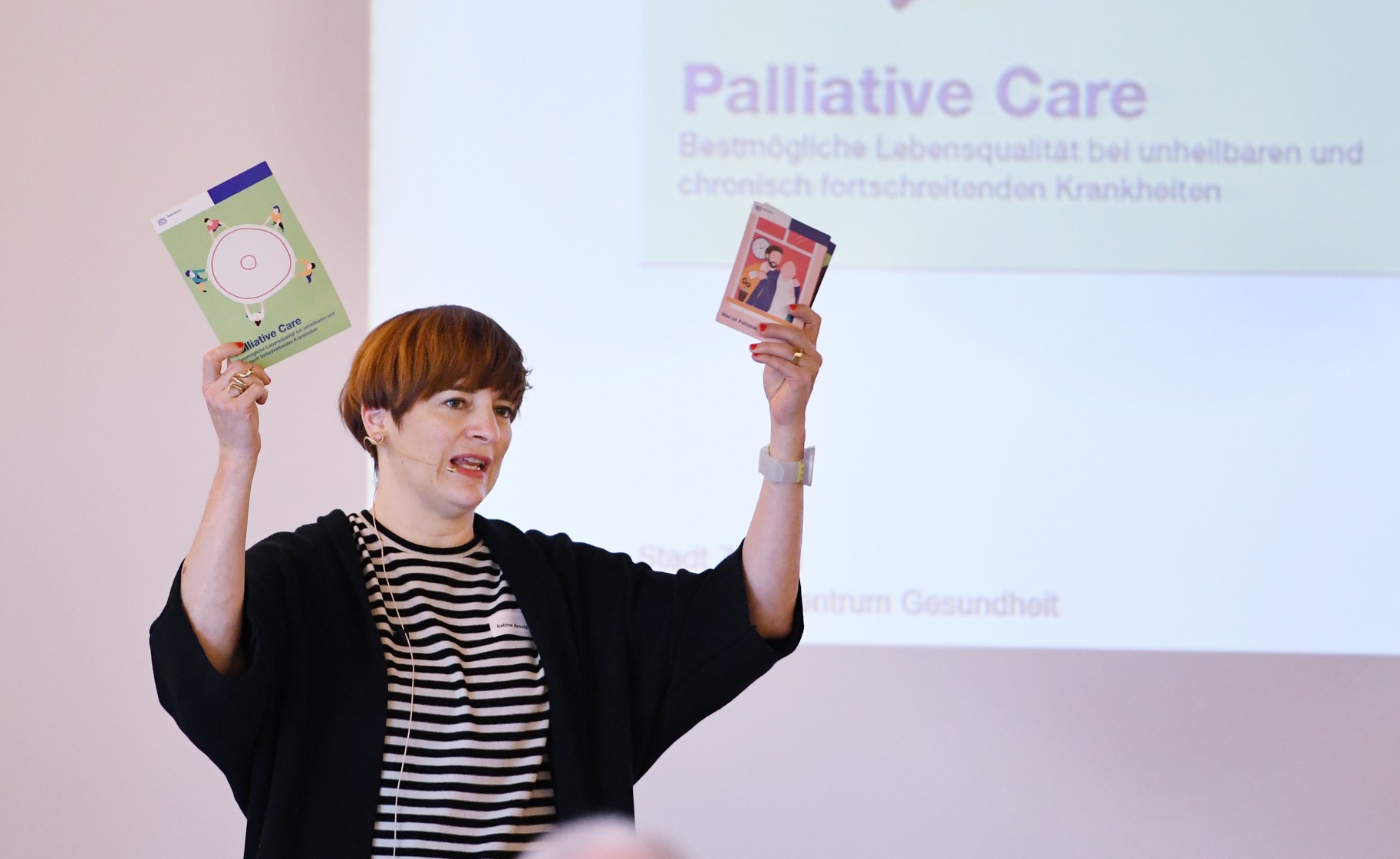 Dozentin hält zwei Flyer in die Luft