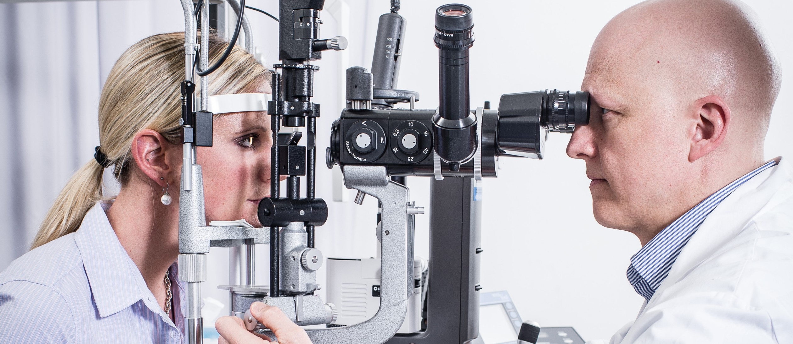 Arzt untersucht das Auge der Patientin an der Spaltlampe