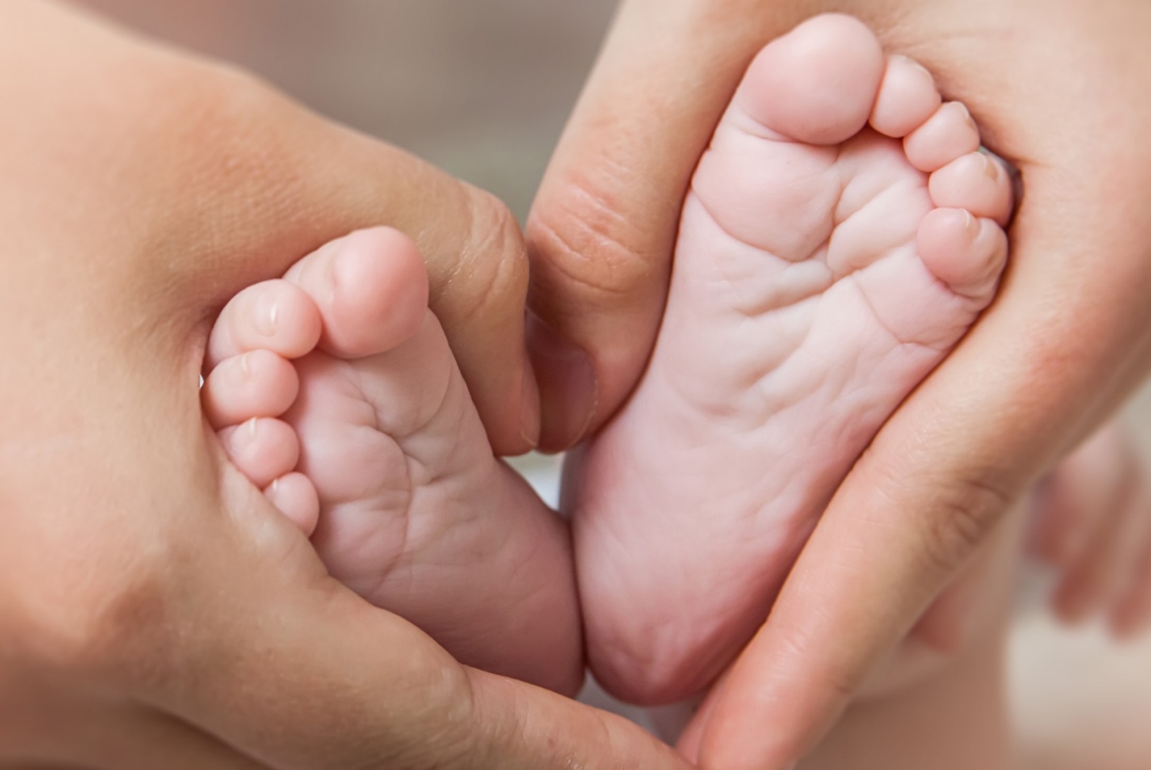 Mutter zeigt Babyfüsse in die Kamera, die dann ein Herzbilden