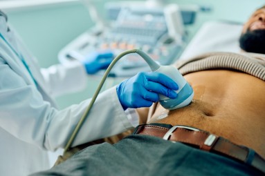 Close up of black man during abdomen ultrasound examination at doctor's office. 