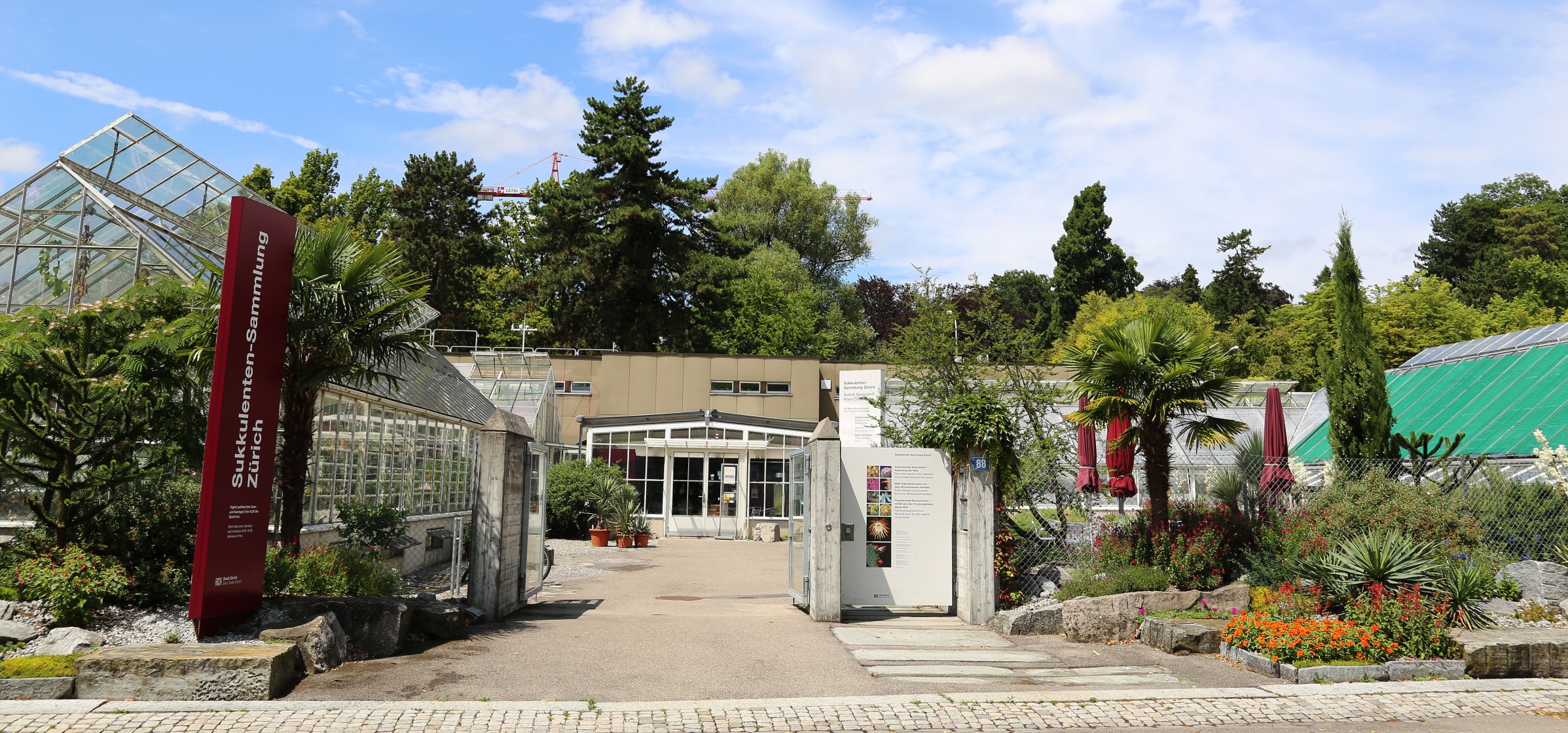 Eingang der Sukkulenten-Sammlung mit Gewächshäusern im Hintergrund