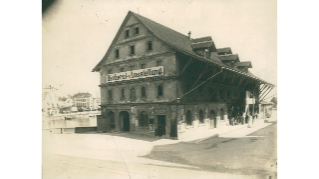 Um 1890, altes Kornhaus vor dem Fraumünster (1897 abgerissen), im unteren Stockwerk befand sich das erste Verkaufslokal des Lebensmittelvereins (LVZ, heute Coop)