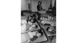 1956, Kinder mit Betreuerin in Feldbetten im Ruheraum der Kinderkrippe Neustadtgasse der Stiftung GFZ (Quelle: Sozialarchiv)