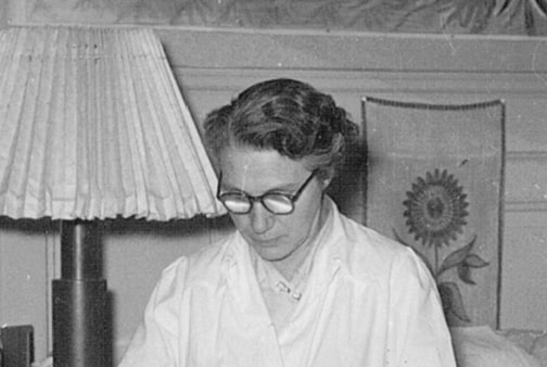 Luise Meyer-Strasser in Schwarz-Weiss mit ernstem Blick, hellem Oberteil und Brille