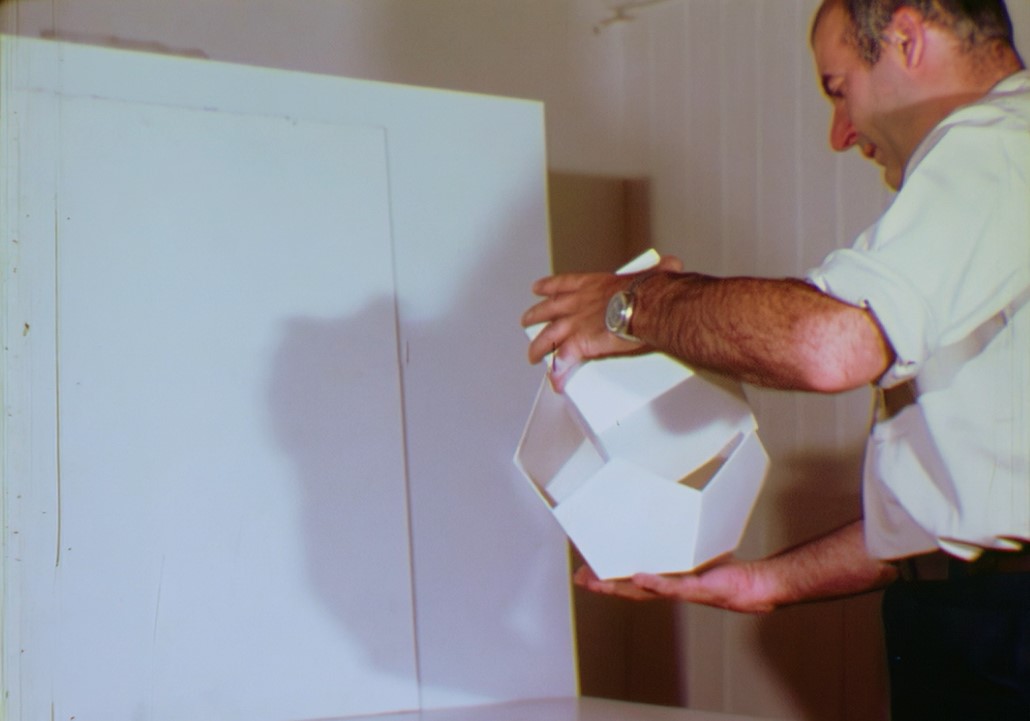 Person mit weisser, geometrischer Form aus Papier in den Händen