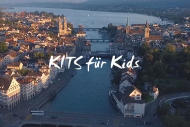 "Kits für Kids"-Schriftzug über einem Foto von der Stadt Zürich aus der Vogelperspektive