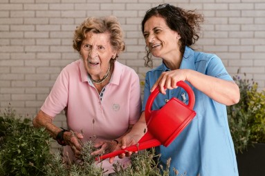 Pflegekraft und ältere Dame beim Gärtnern