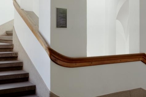Schwarzes Schild mit weisser Schrift im Treppenaufgang