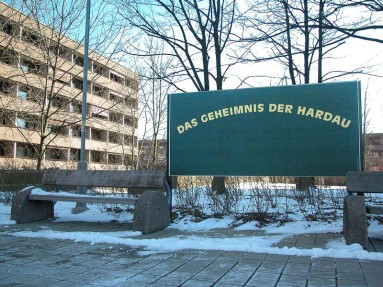 Plakat mit der Aufschrift Das Geheimnis der Hardau, im Hintergrund ein Ausschnitt der Wohnsiedlung Hardau.