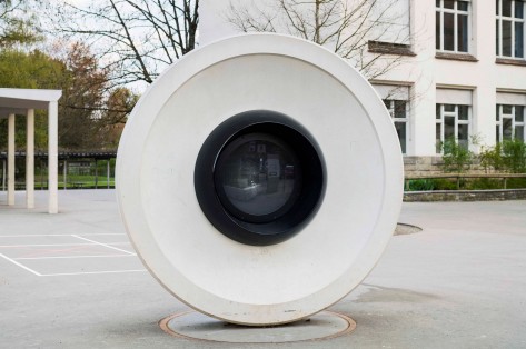 Weisse Sichtbetonplastik «LUEG» die einer Überwachungskamera und einem Auge ähnelt.