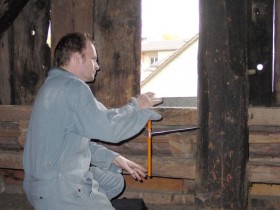 Dendrochronologe im Dachstuhl eines Hauses bei der Entnahme einer Holzprobe mit einem Zuwachsbohrer