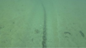 Eine Kette schleift am Seegrund und gräbt eine Schneise in den Untergrund
