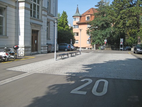 Huttenstrasse. Seitlich längs verlaufende Friesstreifen (ein- und dreireihig), Platzgestaltung mit Granitpflästerung auf gleichem Niveau.