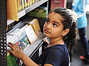 Kind vor Büchergestell