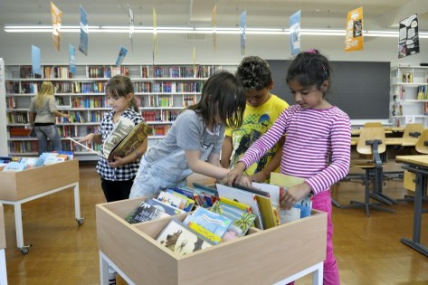 Kinder schmökern in einer Bücherkiste