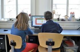 Ein Mädchen und ein Junge sitzen vor einem Computer